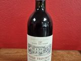 a bottle of red wine sitting on top of a wooden table