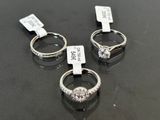three diamond rings with price tags on them sitting on a table
