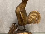 statue d'un coq posée sur une table en verre, avec une étiquette de prix