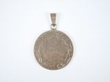 an old silver coin with a face on it on a white surface