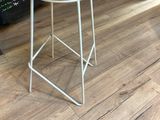 tabouret en métal blanc avec une assise en bois, placé devant un tableau noir
