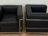 pair of black leather lounge chairs with chrome legs