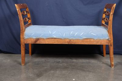 a bench with a blue cushion on it in front of a blue backdrop