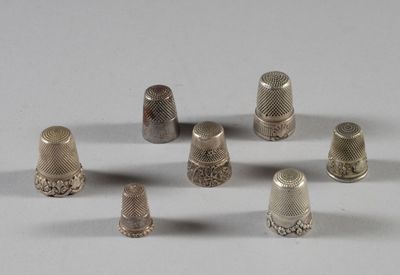 Plusieurs dés à coudre en argent sont disposés en cercle sur une surface blanche