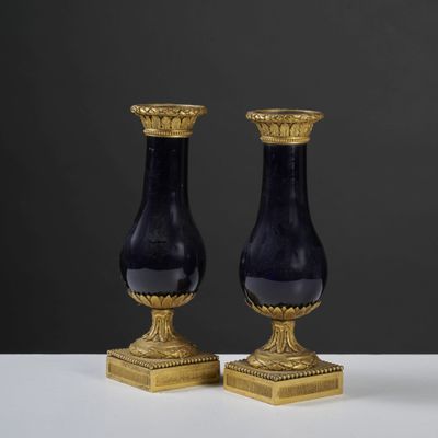 pair of black and gold vases sitting on top of a white table