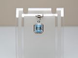 un petit pendentif en cristal bleu présenté dans une vitrine transparente