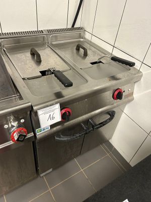 two stainless steel stoves with red knobs in a kitchen
