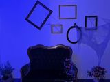 un canapé dans une pièce baignée d'une lumière bleue, avec des tableaux accrochés au mur