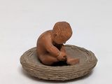a small figurine of a boy sitting on a nest