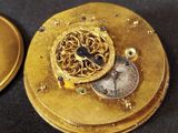 a close up of a gold pocket watch on a black surface