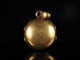 a close up of a gold pocket watch on a black surface