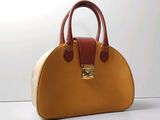 un sac à main beige et marron posé sur une surface blanche