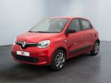 Une voiture rouge est garée dans une pièce au sol noir.