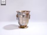 un vase en argent posé sur une surface blanche