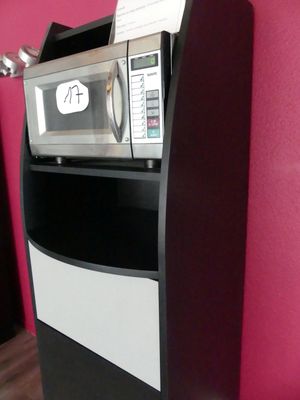un micro-ondes posé sur une étagère noire et blanche