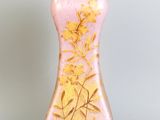 un vase rose orné de fleurs dorées