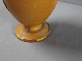 a yellow vase sitting on a table with a gray background