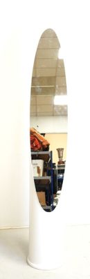 a mirror on a stand in a room with a chair