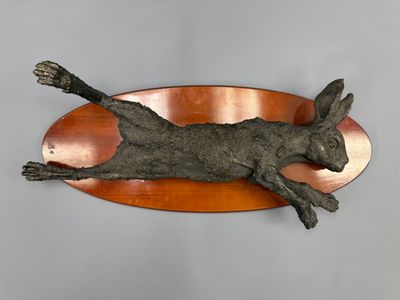 a sculpture of a cat laying on top of a copper plate