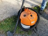 a man standing next to a lawn mower on the side of the road