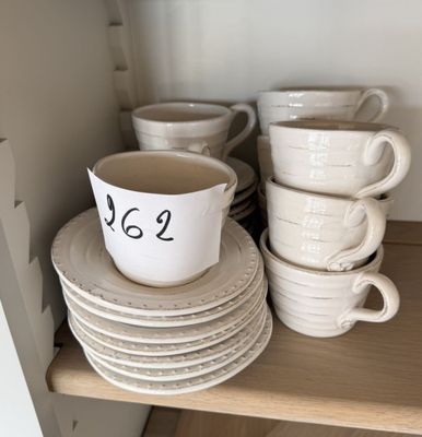 de nombreuses tasses et soucoupes sur une étagère de la cuisine