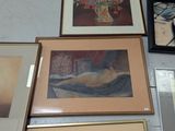 many pictures on the wall of a room with a vase of flowers