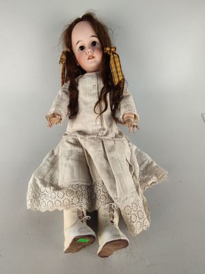 an old fashioned doll sitting on top of a white surface