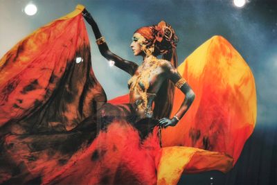 tableau représentant une femme vêtue d'une robe rouge et orange, tenant un éventail