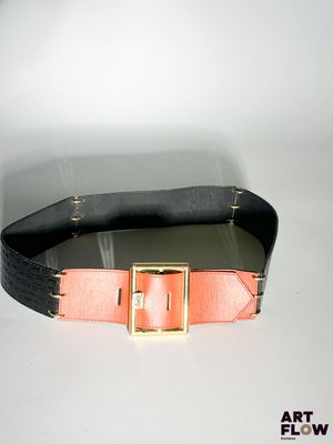 une ceinture noire ornée d'une boucle dorée sur fond blanc