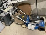 une tondeuse à gazon bleue posée par terre dans un garage