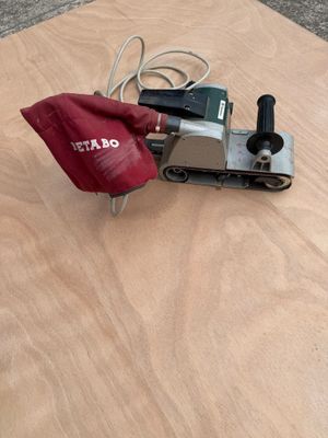 Quelqu'un utilise une ponceuse pour poncer un morceau de contreplaqué.