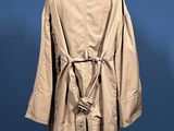 beige trench coat on a mannequin stand against a blue background
