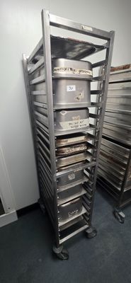many trays of food on a metal rack in a room