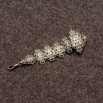 un gros plan d'un bracelet en argent posé sur une surface marron