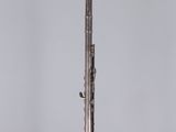 an old silver plated musical instrument on a stand on a gray background