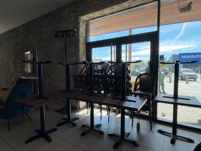 des tables et des chaises devant une fenêtre sur laquelle est accrochée une pancarte