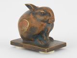 sculpture représentant un lapin posée sur un socle en bois, sur fond blanc