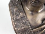 bronze bust of a woman wearing a headdress with a scarf around her neck