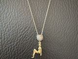 un collier en or orné d'une petite figurine assise sur une surface en cuir noir