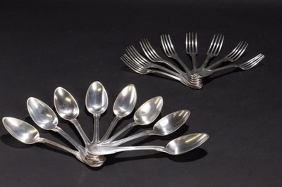 Plusieurs cuillères et fourchettes en argent sont disposées dans une composition florale