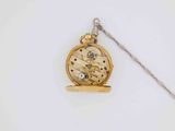 a gold pocket watch with a chain on a white surface