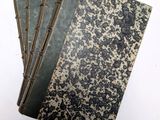 trois vieux livres sont empilés sur une surface blanche