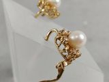 a close up of a pair of earrings with pearls on them