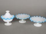three white and blue glass vases sitting on top of a table
