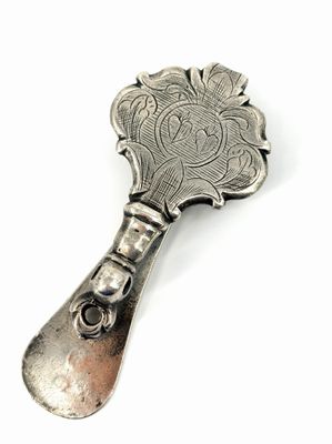 une cuillère en argent avec un manche en argent posée sur une surface blanche