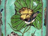 a green vase with a bird and flowers painted on it