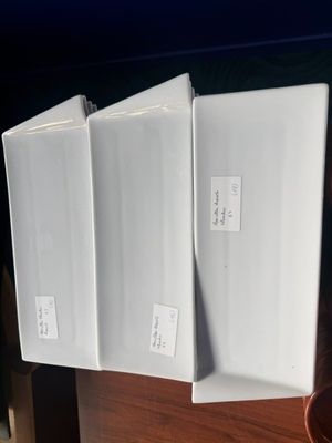 trois chemises blanches posées sur un bureau en bois, à côté d'une plante