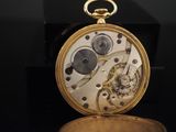 a close up of a gold pocket watch on a black surface