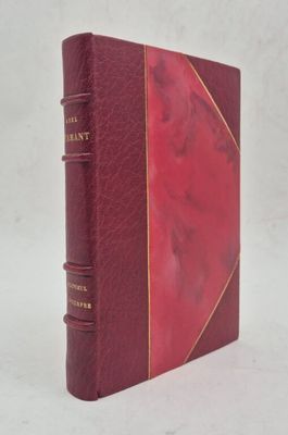 un vieux livre à la couverture rouge posé sur une surface blanche