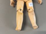 a wooden mannequin sitting on a gray surface